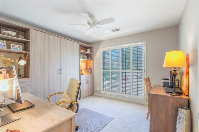 office area with visible vents, a ceiling fan, and light colored carpet