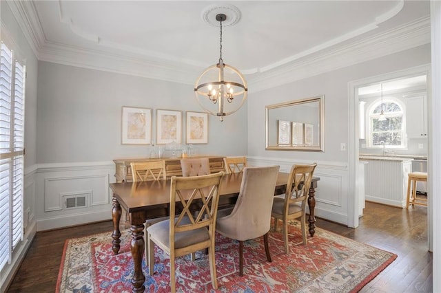 dining room with a notable chandelier, visible vents, ornamental molding, wainscoting, and dark wood finished floors