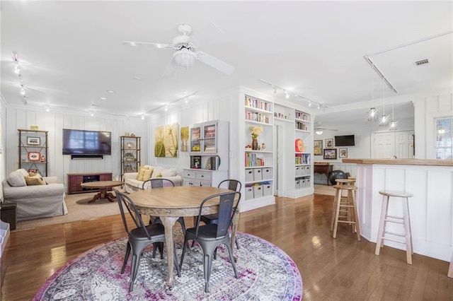 dining room with visible vents, a ceiling fan, a decorative wall, and wood finished floors