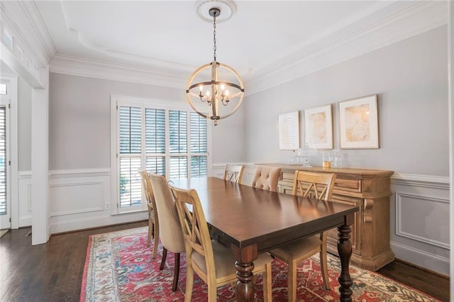 dining area with ornamental molding, dark wood finished floors, a wainscoted wall, and a notable chandelier