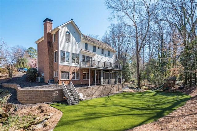 rear view of property featuring a deck, brick siding, stairway, a lawn, and a chimney