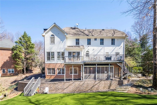 rear view of property with brick siding, a sunroom, stairway, and a yard