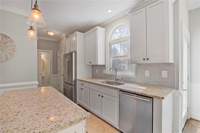 kitchen with appliances with stainless steel finishes, ornamental molding, a sink, light stone countertops, and backsplash