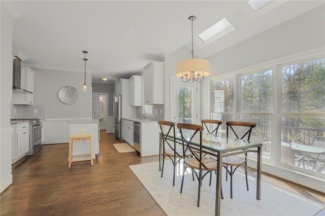 dining space featuring ornamental molding, dark wood finished floors, lofted ceiling with skylight, and an inviting chandelier