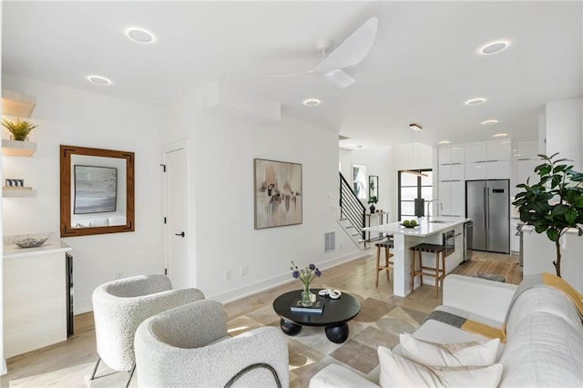 living room featuring sink, ceiling fan, and light hardwood / wood-style flooring