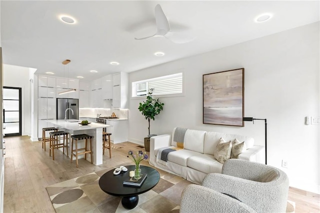 living room with ceiling fan, light hardwood / wood-style flooring, and sink