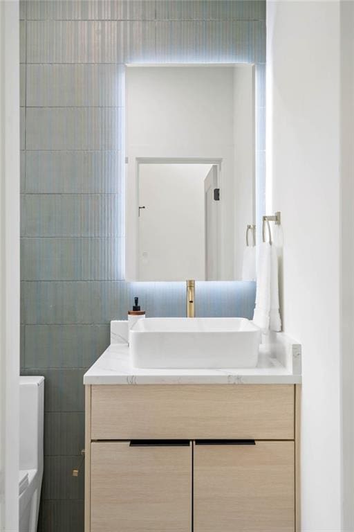 bathroom featuring toilet, tile walls, and vanity