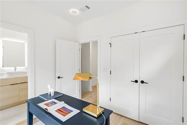 home office with sink and light wood-type flooring