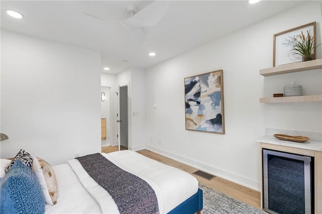 bedroom with beverage cooler, ceiling fan, and light hardwood / wood-style floors