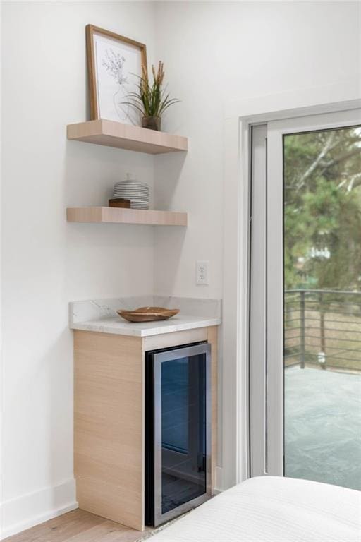 bar featuring light brown cabinetry, beverage cooler, and light wood-type flooring