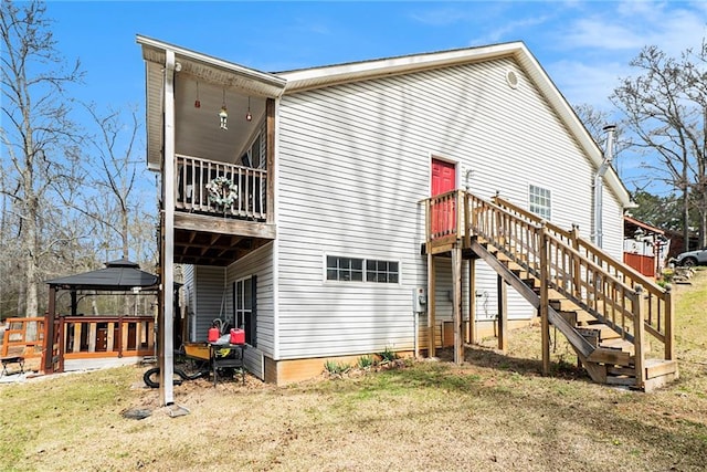 back of property featuring a yard, a gazebo, and stairs