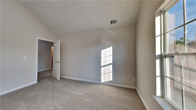 empty room featuring visible vents, lofted ceiling, carpet, and baseboards