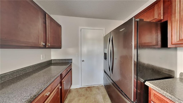 kitchen with dark stone counters, refrigerator with ice dispenser, and a textured ceiling