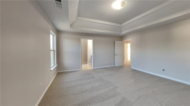 interior space featuring visible vents, baseboards, a tray ceiling, carpet flooring, and a textured ceiling