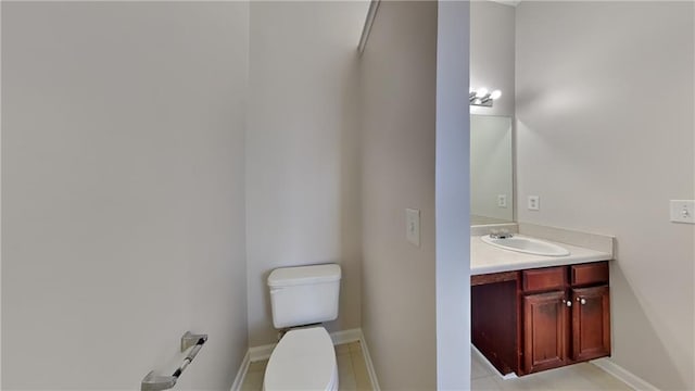 half bath featuring vanity, toilet, and baseboards