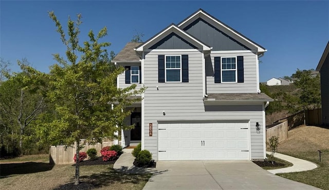 view of front facade featuring an attached garage, board and batten siding, driveway, and fence