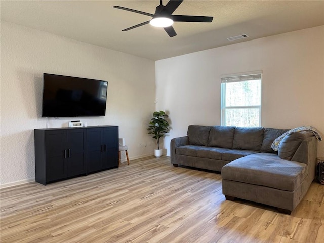 living area featuring light wood-type flooring, baseboards, a ceiling fan, and visible vents