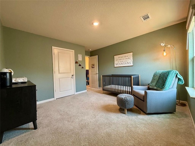 sitting room with visible vents, baseboards, carpet, and a textured ceiling