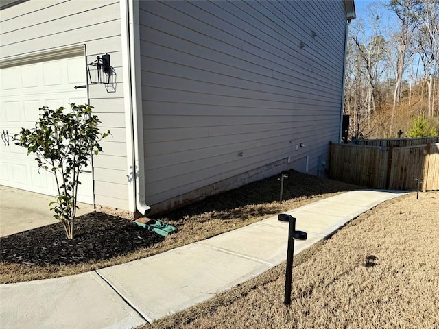 view of property exterior featuring a garage and fence
