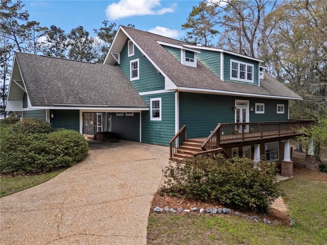 view of front of home featuring driveway, a shingled roof, and a deck