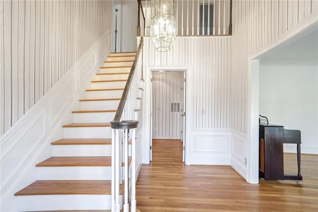 staircase with hardwood / wood-style floors and a chandelier