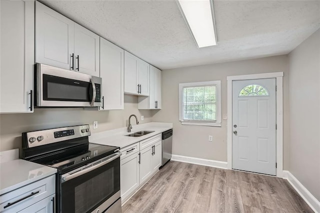 1002 Ira St SW, Atlanta, GA 30310 - kitchen with baseboards, light wood-type flooring, a textured ceiling, a sink, and appliances with stainless steel finishes