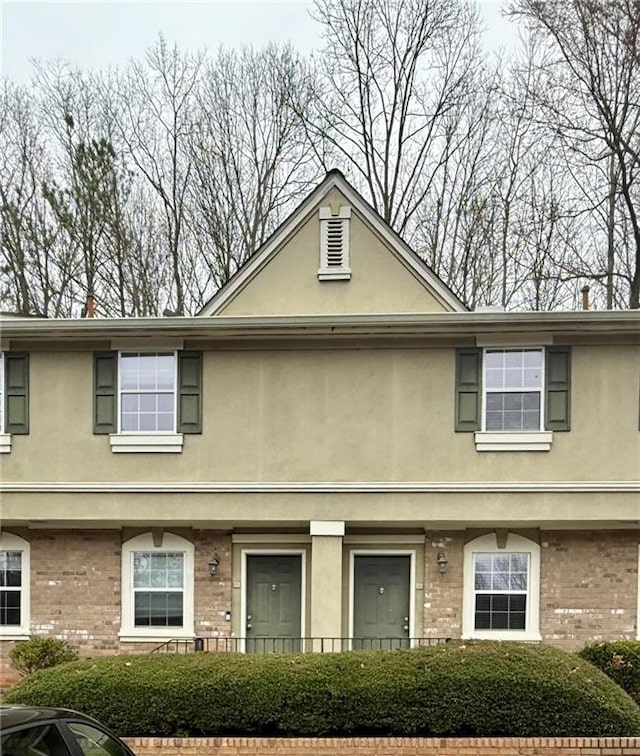 view of property featuring brick siding and stucco siding