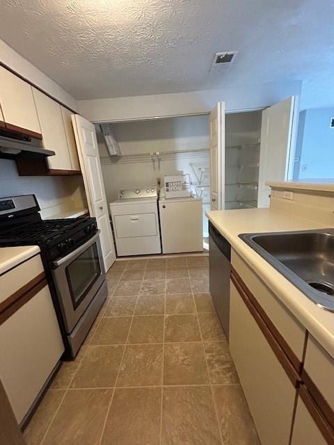 kitchen with white cabinetry, stainless steel appliances, sink, a textured ceiling, and washer and clothes dryer