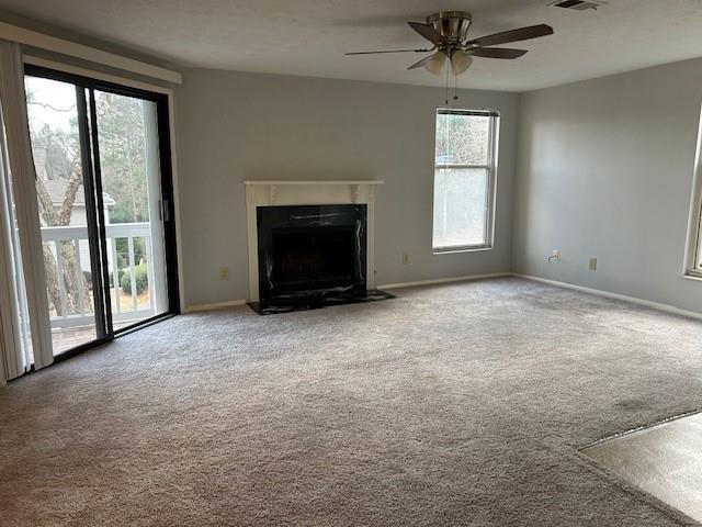 unfurnished living room featuring ceiling fan, a premium fireplace, and carpet