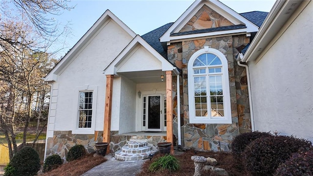 property entrance with stucco siding, stone siding, and a shingled roof