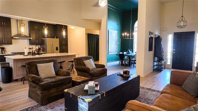 living area featuring baseboards, light wood-type flooring, a high ceiling, and ornamental molding