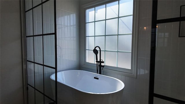 bathroom featuring tile walls and a freestanding bath