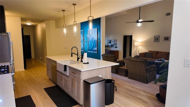 kitchen featuring open floor plan, light countertops, light wood-style floors, and a sink