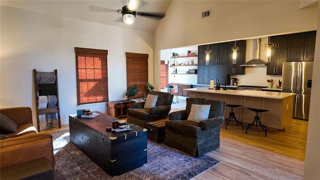 living room featuring high vaulted ceiling, a ceiling fan, visible vents, and light wood-type flooring