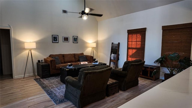 living room with visible vents, high vaulted ceiling, wood finished floors, baseboards, and ceiling fan