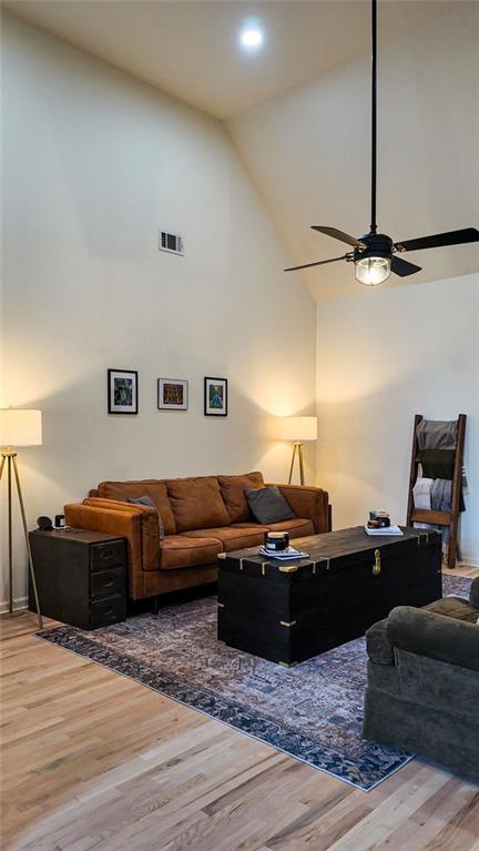 living room featuring visible vents, high vaulted ceiling, a ceiling fan, and wood finished floors