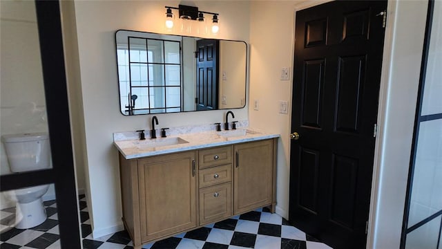 bathroom featuring tile patterned floors, double vanity, toilet, and a sink