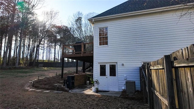 rear view of property with a wooden deck, fence, cooling unit, and a shingled roof