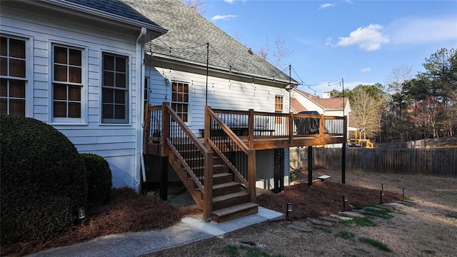 rear view of house featuring a wooden deck, fence, stairway, and a shingled roof