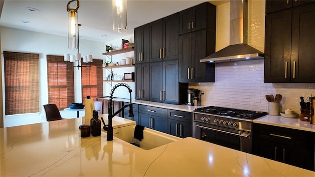 kitchen with tasteful backsplash, a sink, wall chimney range hood, stainless steel range, and open shelves