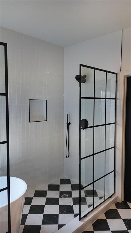 bathroom with tile patterned floors, tiled shower, a freestanding bath, and tile walls