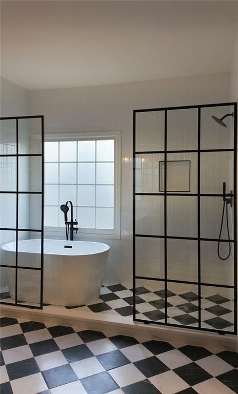 bathroom with tile patterned floors, a freestanding tub, and a tile shower