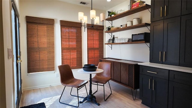 dining area with visible vents, light wood-style floors, and an inviting chandelier