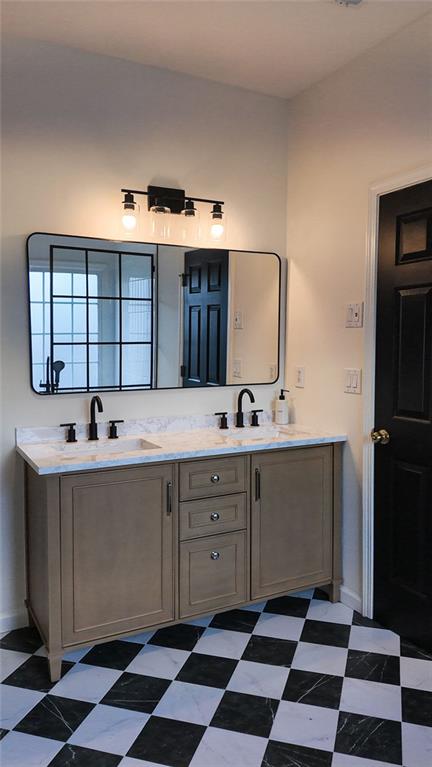 full bath featuring tile patterned floors, double vanity, and a sink