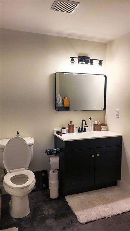 bathroom featuring visible vents, toilet, concrete flooring, and vanity