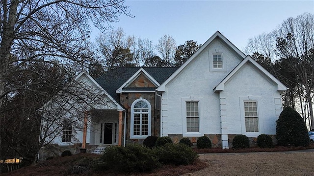 traditional home featuring stone siding and stucco siding