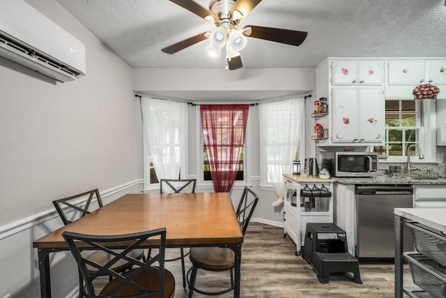 dining area with a ceiling fan, a wall unit AC, wood finished floors, and a textured ceiling