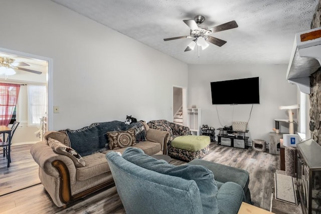 living room featuring a ceiling fan, vaulted ceiling, stairs, and wood finished floors