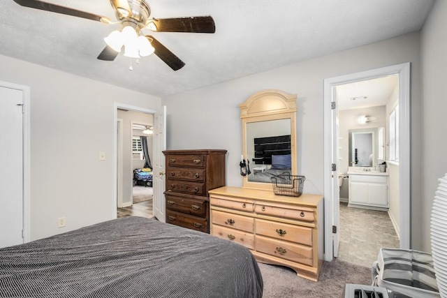 bedroom with light carpet, ensuite bath, and ceiling fan