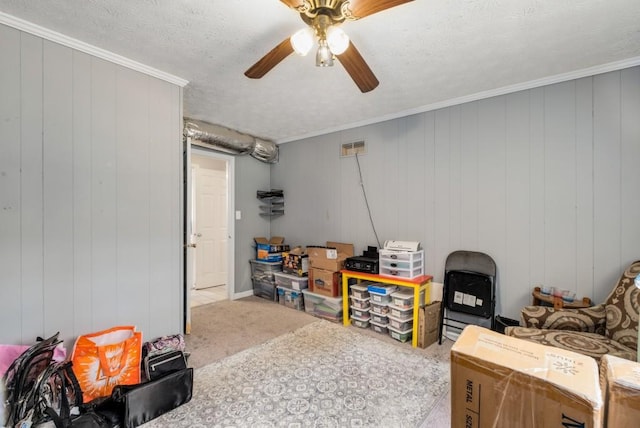 interior space featuring ceiling fan, crown molding, carpet flooring, and a textured ceiling